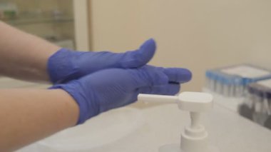 Doktor ellerini eldivenlerle sterilize ediyor. Eldivenli eller, dezenfektan. Virüs ve bakteri.
