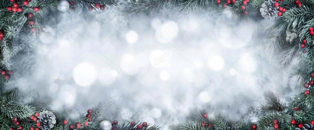 Christmas Background with frosty fir branches as a frame around silver bokeh copy space