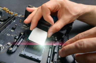 Bilgisayar donanımı parçaları birleştiren bir teknisyenin elleri, yeni, parlak bir işlemci ana karta monte edilirken, stüdyo kapanıyor