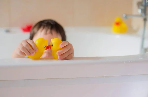Happy little baby in the bathroom playing with rubber yellow dots. Hygiene and care for young children. — Stock Photo, Image