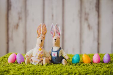 Beyaz ahşap arka planda çimlerde yumurta ve paskalya tavşanı