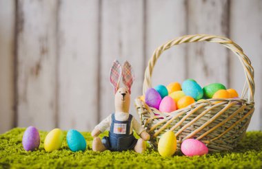 Beyaz ahşap arka planda çimlerde yumurta ve paskalya tavşanı