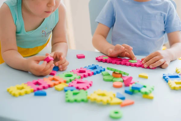 Un garçon et une fille recueillent un puzzle mou à la table. Frère et sœur s'amusent à jouer ensemble dans la chambre. — Photo