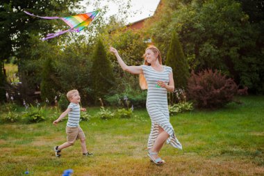 Anne oğul oyun aktif iyi eğlenceler açık havada mutlu annelik çocukluk gençlik çocuk sağlık eğitimi, aktif dinlenme doğa eğlence ana çocuk bakımı yaşam tarzı anneler günü batan güneşin. Uçurtma çalıştırmak çimen