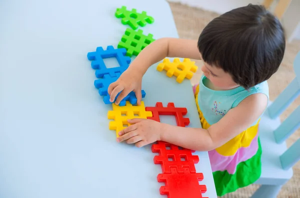 一个3岁的孩子在一个有彩色玩具块的桌旁玩耍 孩子们在幼儿园或房间里玩教育玩具 学龄前儿童聚集在桌旁 用塑料块拼凑出字谜 — 图库照片