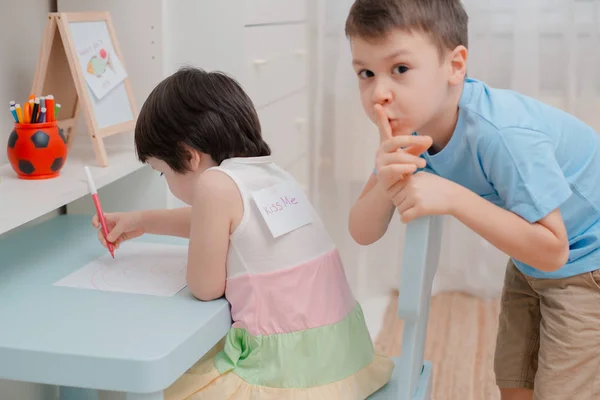 Irmão enfia um peixe de papel nas costas das irmãs em abril tolos Dia. Humor infantil em 1 de abril. Piadas e diversão — Fotografia de Stock