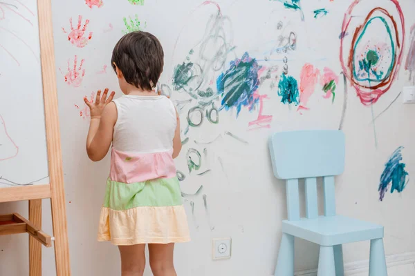 Uma menina, de 3 anos, pintou um olhar arqueado com tinta e um pincel na parede de seu quarto . — Fotografia de Stock