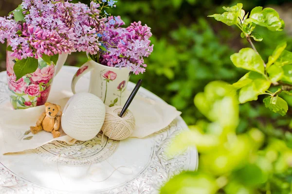 White wooden chair table with a bouquet of lilacs in the spring garden.