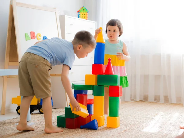 Crianças pré-escolares felizes brincam com blocos de brinquedo. — Fotografia de Stock