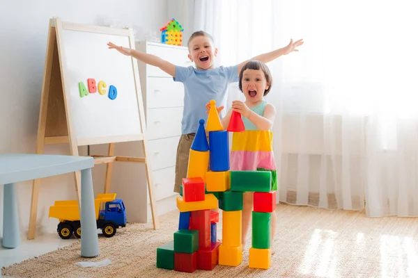 Crianças pré-escolares felizes brincam com blocos de brinquedo. — Fotografia de Stock