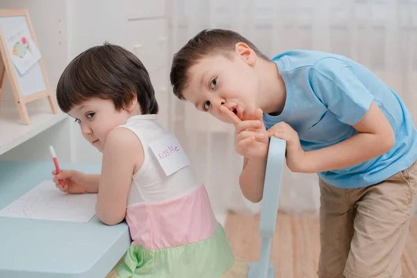 O irmão enfia um peixe de papel nas costas das irmãs no dia do tolo de Abril. Humor infantil em 1 de abril. Piadas e diversão — Fotografia de Stock