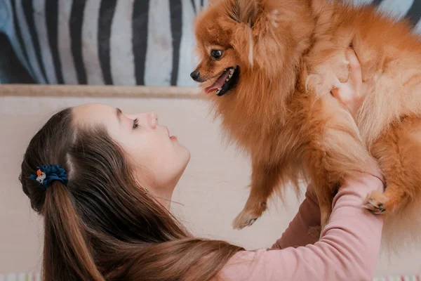 Teenagermädchen mit Hunderasse Spitz freut sich mit Haustier zu Hause auf dem Fußboden. — Stockfoto