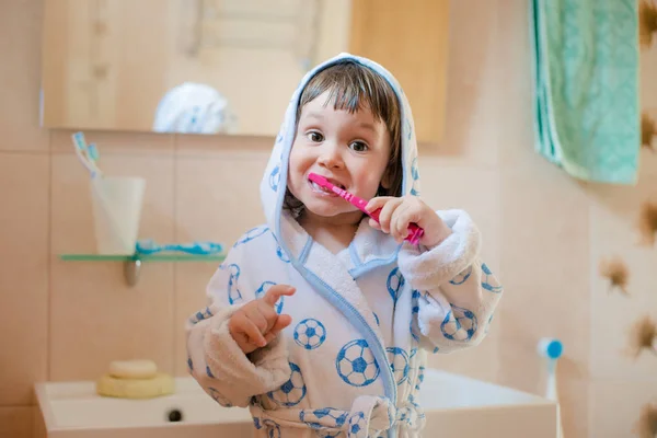 Ένα κοριτσάκι ή ένα παιδί βουρτσίζει τα δόντια της στο μπάνιο. Υγιεινή της στοματικής κοιλότητας. — Φωτογραφία Αρχείου