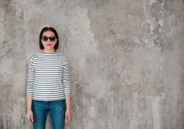 güneş gözlüğü yüksek moda portre genç zarif genç kız kot pantolon ve çizgili bir ceket, kırmızı ruj, parlak moda görüntü beton bir duvara karşı duruyor. boş alan. Mocap için yer
