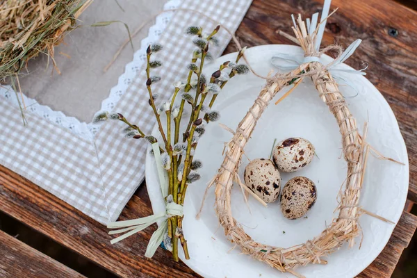 Nid décoratif de paille sur une assiette avec oeuf de caille de Pâques sur une table de jardin de fête servie à l'extérieur. Ferme. Style rustique . — Photo