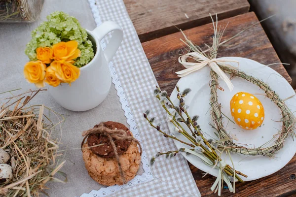 Nid décoratif de paille sur une assiette avec oeuf de caille de Pâques sur une table de jardin de fête servie à l'extérieur. Ferme. Style rustique . — Photo