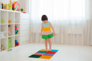 Bebek ayak masajı minderinde yeni yürümeye başlayan çocuk. Ortopedik masaj halısı üzerinde bacak egzersizleri. Düz taban ve halluks valgus önleme