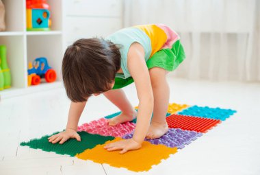 Bebek ayak masajı minderinde yeni yürümeye başlayan çocuk. Ortopedik masaj halısı üzerinde bacak egzersizleri. Düz taban ve halluks valgus önleme