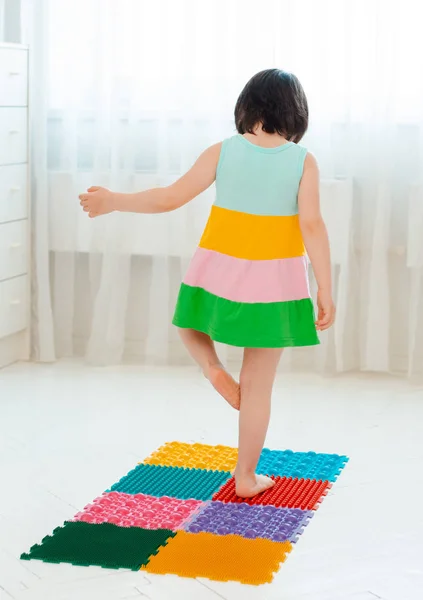 幼儿脚底按摩床上的小孩。在骨科按摩地毯上练习腿。预防扁足和假肢 — 图库照片