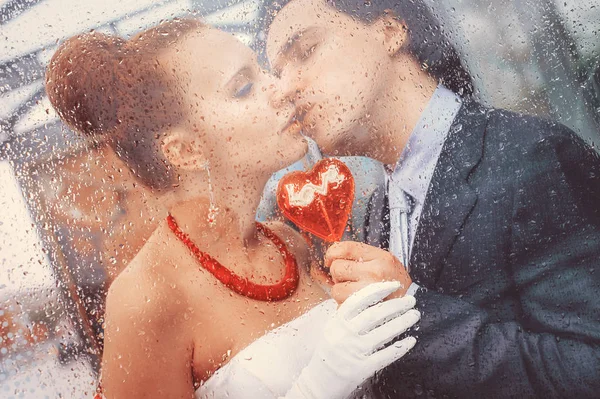 Kärleksfulla par kysser på läpparna Visa genom det våta glaset i dropparna efter regnet. Royaltyfria Stockfoton