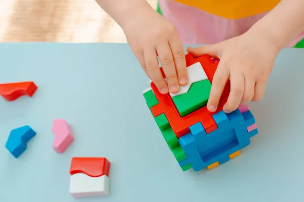 Zbliżenie rąk dziecka zbierać sorter puzzle. Kostka z wstawionymi geometrycznymi kształtami i kolorowymi plastikowymi klockami. — Zdjęcie stockowe
