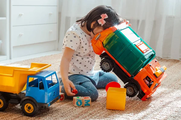 The concept of childhood and people is a happy three year old girl playing with a toy car at home. — Stock Photo, Image