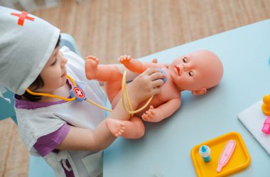 Küçük kız 3 yaşında okul öncesi bebek ile doktor oynuyor. Çocuk bir enjeksiyon oyuncak yapar.