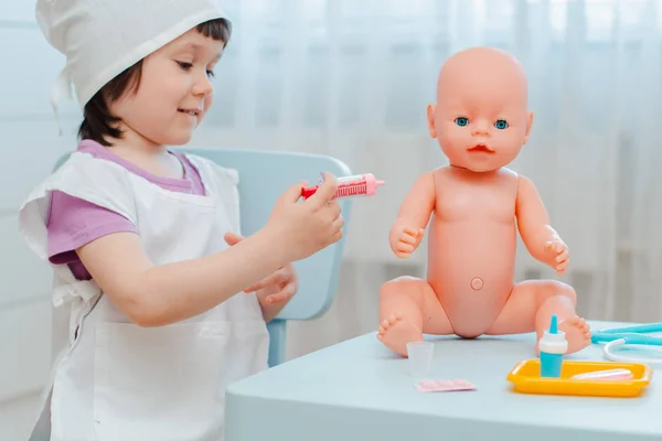 Μικρό κορίτσι 3 ετών νηπιαγωγίας παίζοντας γιατρό με κούκλα. Το παιδί κάνει ένα παιχνίδι ένεσης. — Φωτογραφία Αρχείου