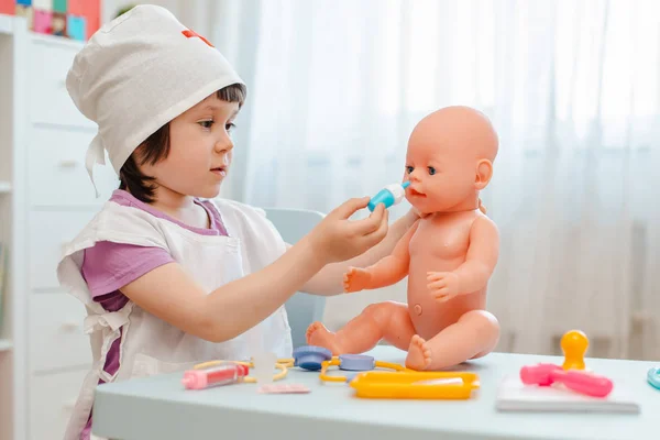 Niña de 3 años de edad preescolar jugando médico con muñeca. El niño hace un juguete de inyección . — Foto de Stock