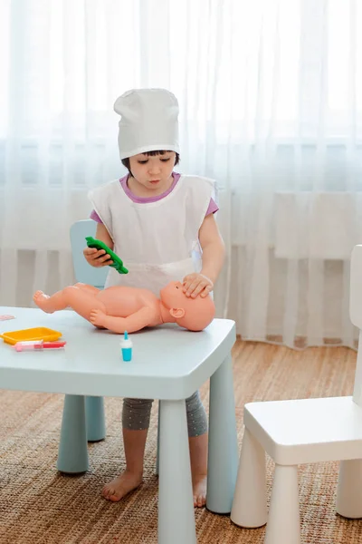 Küçük kız 3 yaşında okul öncesi bebek ile doktor oynuyor. Çocuk bir enjeksiyon oyuncak yapar. — Stok fotoğraf
