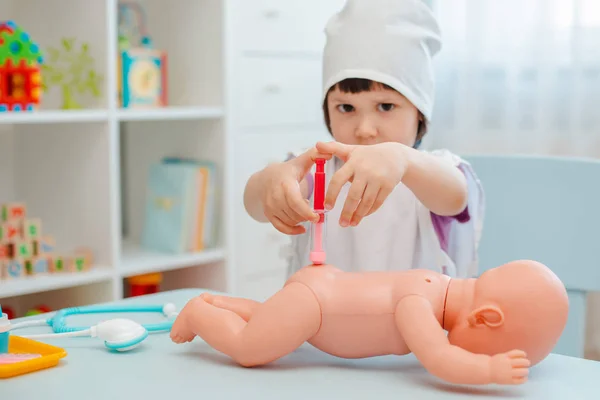 Dziewczynka 3 lat przedszkoler gra lekarz z lalką. Dziecko wykonuje zabawkę do wstrzykiwań. — Zdjęcie stockowe
