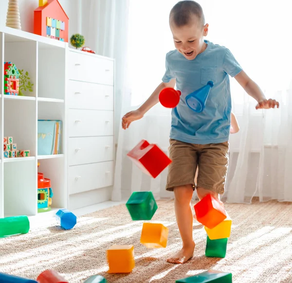 Irmãozinho e irmã correr ao redor do quarto espalhando pernas brinquedo raznocvetnye plastikovye blocos . — Fotografia de Stock