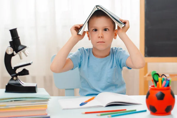 Niño de la escuela sentado en el aula de casa tumbado escritorio lleno de libros material de formación escolar durmiendo perezoso aburrido — Foto de Stock