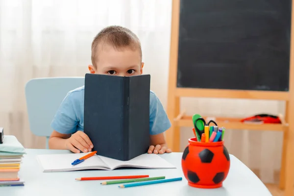 Niño de la escuela sentado en el aula de casa tumbado escritorio lleno de libros material de formación escolar durmiendo perezoso aburrido — Foto de Stock