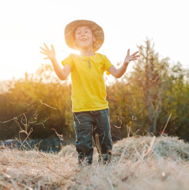 küçük çocuk köyde büyük bir samanlık yükseklikte oturuyor. Çocuk çiftçi.
