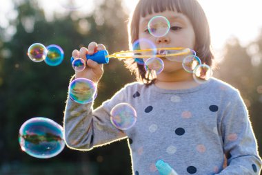 Gün batımı arka plan ile Playground üzerinde kabarcıklar üfleme Çocuklar küçük kız