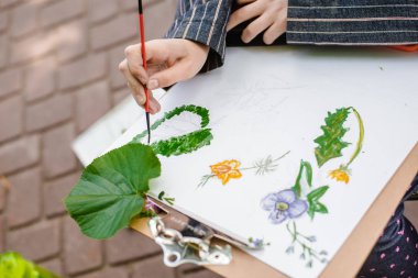 yaratıcı sanatçı renkli bir resim çizer. Açık havada boyama işleminde ellerin ve fırçanın yakın çekim