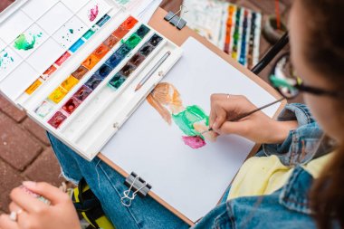 yaratıcı sanatçı renkli bir resim çizer. Açık havada boyama işleminde ellerin ve fırçanın yakın çekim