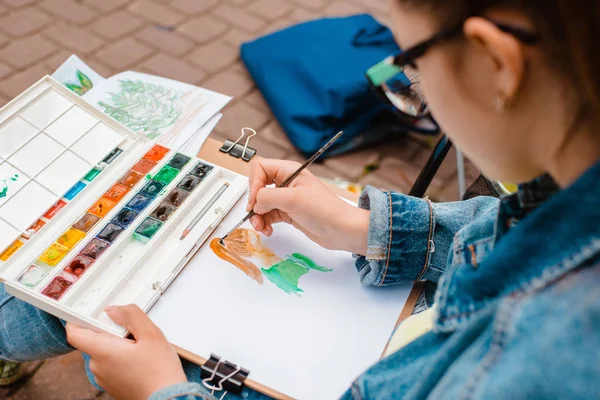 yaratıcı sanatçı renkli bir resim çizer. Açık havada boyama işleminde ellerin ve fırçanın yakın çekim
