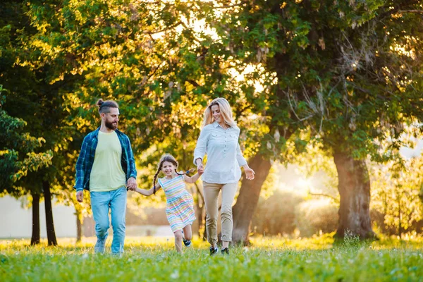 Mutlu genç aile dışarıda yeşil doğada birlikte vakit geçiriyor..