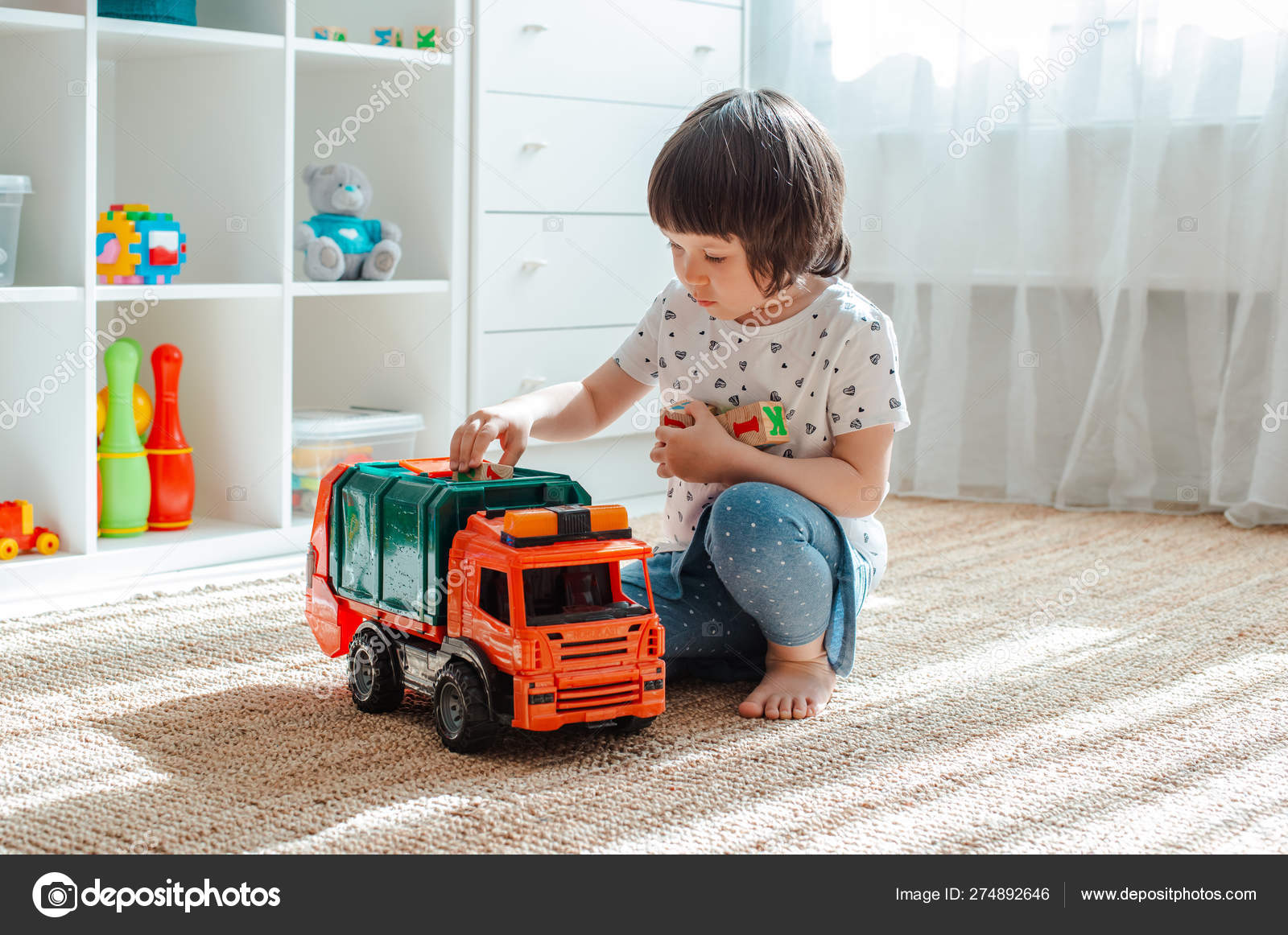 O conceito de infância e as pessoas é uma menina feliz de três anos  brincando com um carro de brinquedo em casa . fotos, imagens de © Shangarey  #274892646