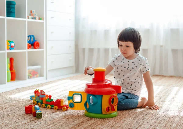 Niño jugando con bloques de juguetes de colores en el suelo en la habitación Juguetes educativos para niños pequeños. Clasificador para bebé o niño pequeño —  Fotos de Stock