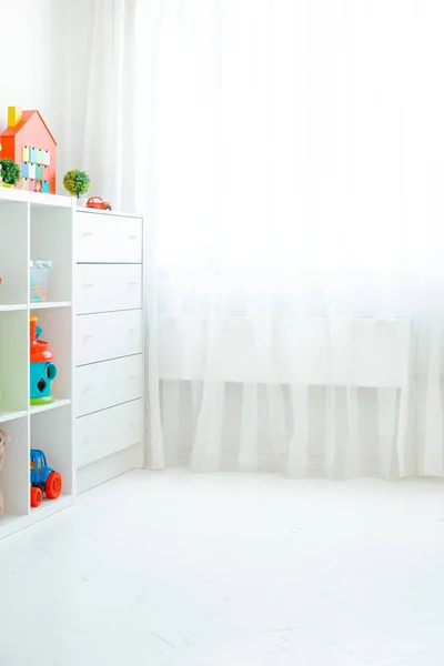 Copie o espaço de uma parede vazia em um quarto infantil simples com um piso de madeira branca e uma janela grande e leve . — Fotografia de Stock