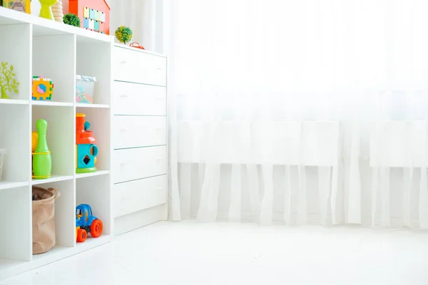 Kopieer de ruimte van een lege muur in een eenvoudige kinderkamer met een witte houten vloer en een groot en licht raam. — Stockfoto