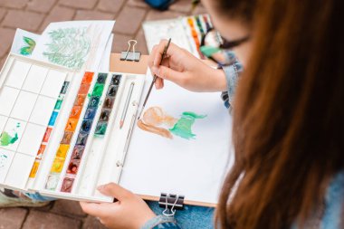 yaratıcı sanatçı renkli bir resim çizer. Açık havada boyama işleminde ellerin ve fırçanın yakın çekim