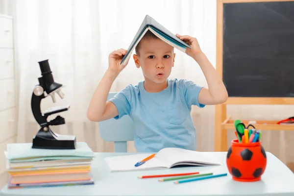 School boy sitting at home classroom lying desk filled with books training material schoolchild sleeping lazy bored — Stock Photo, Image