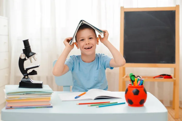 Niño de la escuela sentado en el aula de casa tumbado escritorio lleno de libros material de formación escolar durmiendo perezoso aburrido — Foto de Stock