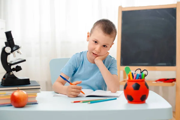 Niño de la escuela sentado en el aula de casa tumbado escritorio lleno de libros material de formación escolar durmiendo perezoso aburrido — Foto de Stock