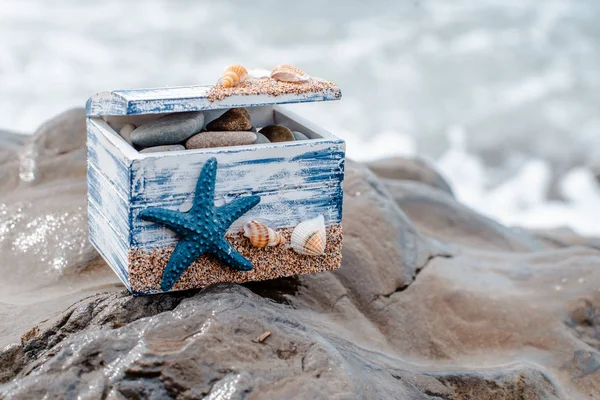 Wooden decorative Chest with sea shells and blue star on the sea coast. — Stock Photo, Image