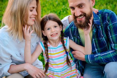 Mutlu genç aile dışarıda yeşil doğada birlikte vakit geçiriyor..